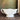 White ceramic bowl with handles on a wooden surface with a textured green wall background
